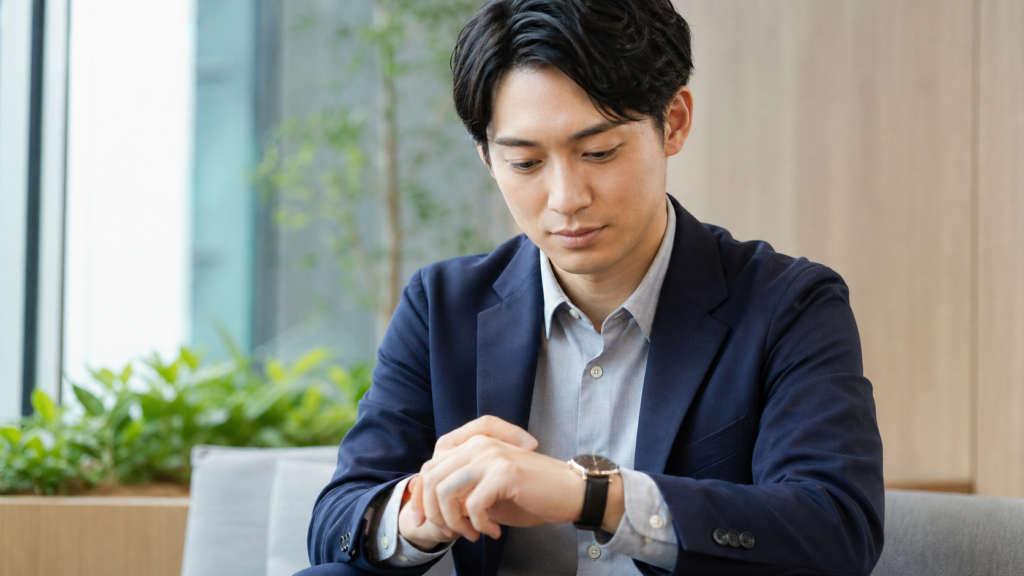 オフィスで仕事用腕時計を確認する20代の日本人ビジネスパーソン